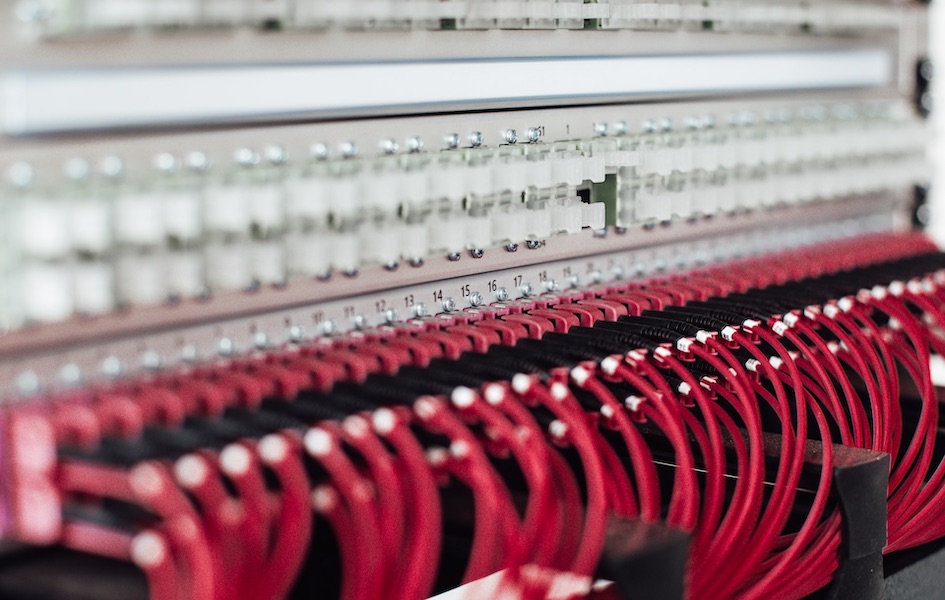 An assemblage of red cables is run into various ports in the IT configuration of the company’s servers. 